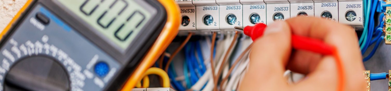 Hand of an electrician with multimeter probe at an electrical sw Hand of an electrician with multimeter probe at an electrical sw
